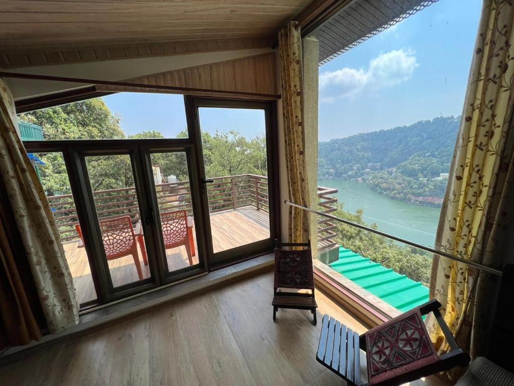 een kamer met een balkon met uitzicht op een rivier bij Little Heaven in Nainital