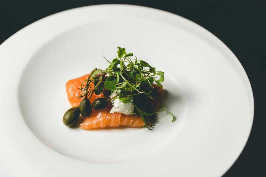 a plate of food with salmon and greens on it at Dhawa Yura Kyoto - Banyan Group in Kyoto