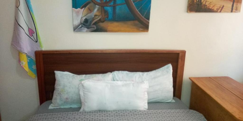 a bed with two pillows and a painting on the wall at The Red Nest Nahashon Kimemia One Bedroom in Nairobi