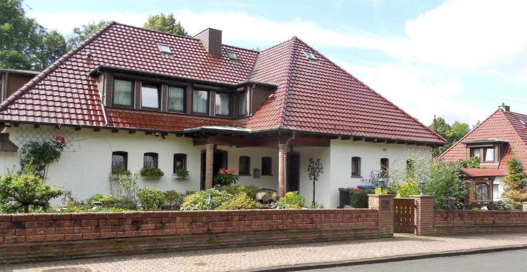 ein Haus mit rotem Dach und einem Steinzaun in der Unterkunft Ferienwohnungen an der Hufeland-Therme in Bad Pyrmont