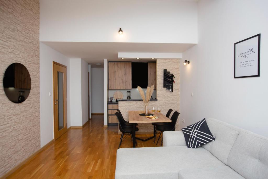 een woonkamer met een witte bank en een tafel bij Apartment Cejf Mostar in Mostar