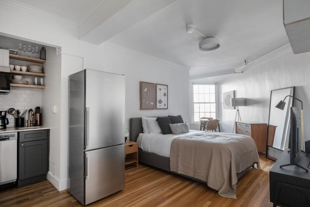 a bedroom with a bed and a kitchen with a refrigerator at Brookline Studio w Gym nr Green Line BOS-476 in Brookline