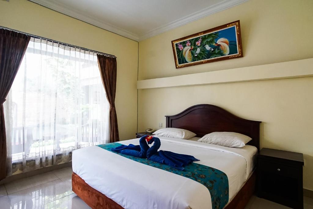 una camera da letto con un letto con un accappatoio blu sopra di Taman Ayu Legian Hotel a Legian