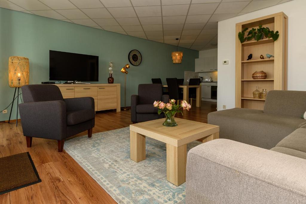 ein Wohnzimmer mit einem Sofa, Stühlen und einem TV in der Unterkunft Zanddijk 113, Julianadorp aan Zee in Julianadorp