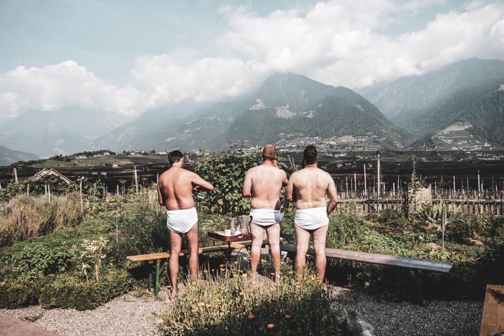 three shirtless men standing in front of a table overlooking a mountain at Hosler in Merano