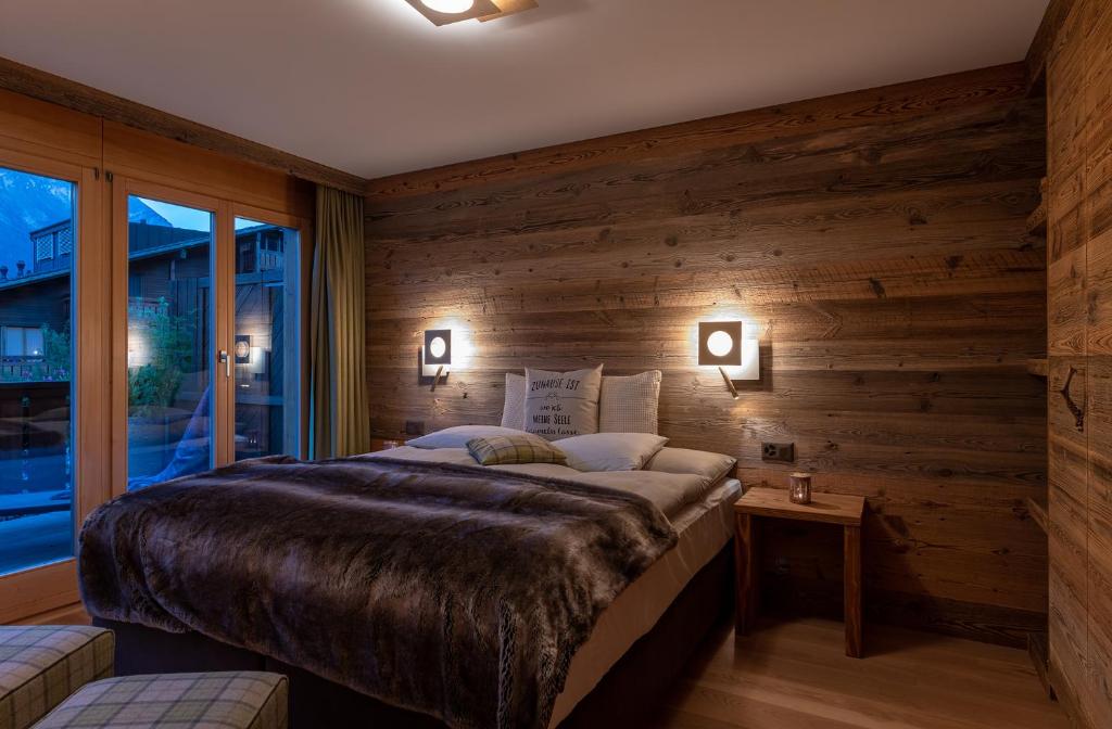 a bedroom with a wooden wall with a bed and a window at SALZANO Apartments in Interlaken