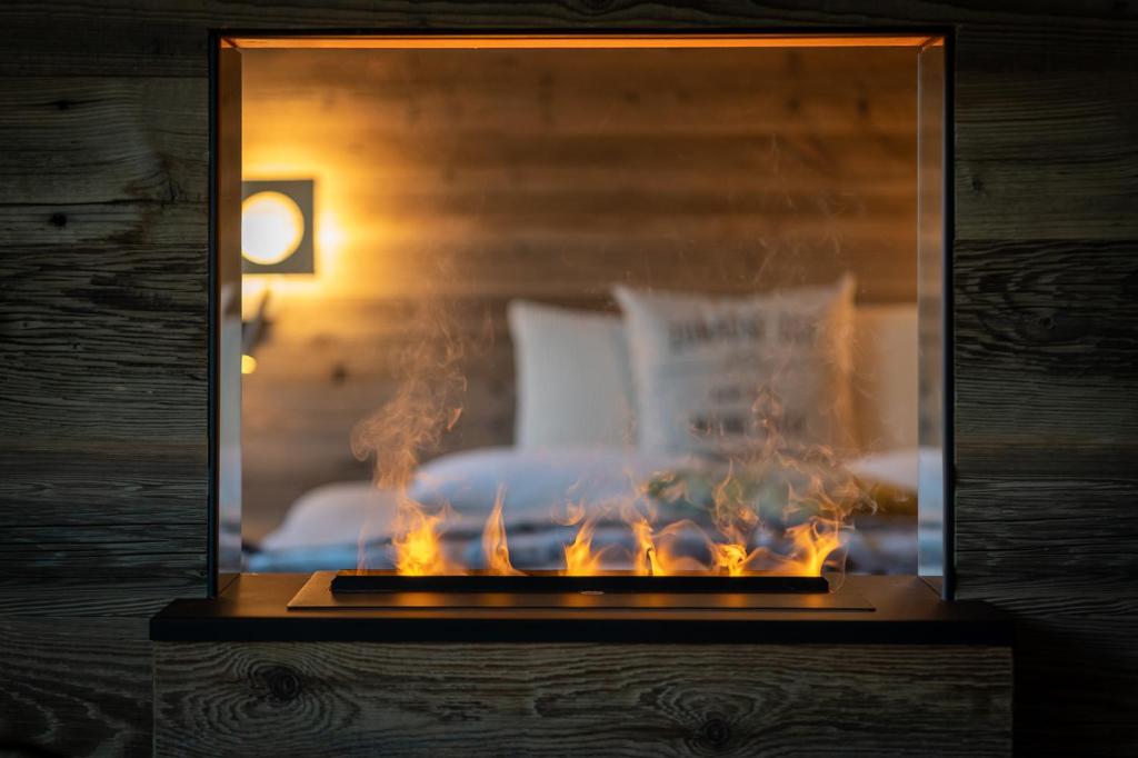 a glass box with a fire place in front of a bed at SALZANO Apartments in Interlaken