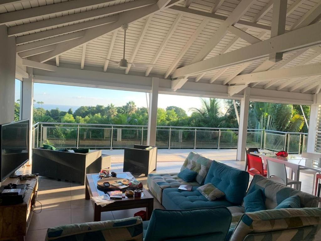 een woonkamer met een blauwe bank en een tafel bij Villa Écrin de Nature in Sainte-Rose