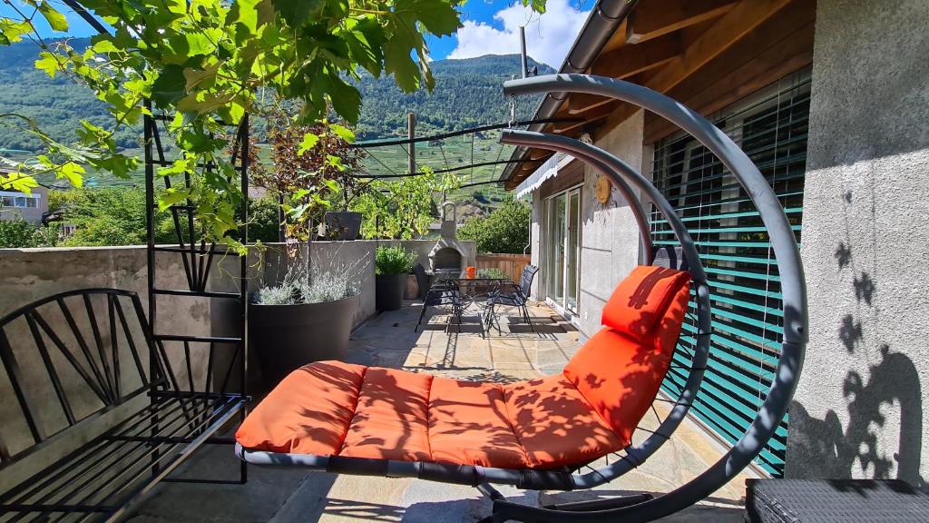 a bench with an orange cushion sitting on a patio at Chez Pewee, beau duplex en ville, parc privé in Martigny-Ville
