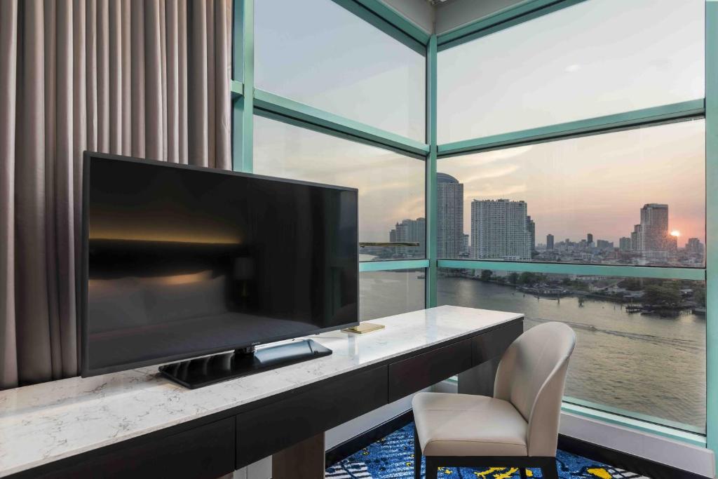 A desk, chair, and television face a broad window over the river and city skyline.