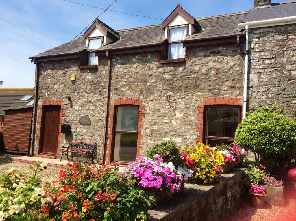 a stone house with flowers in front of it at Y Buarth in Llansaint