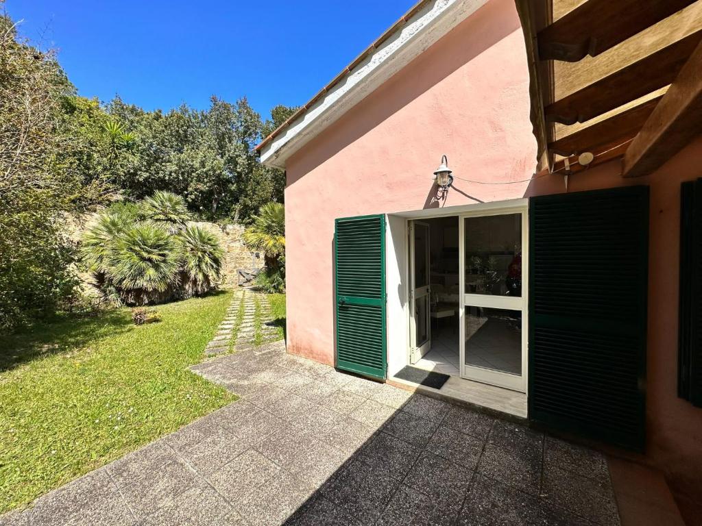 una casa rosa con una puerta verde y un patio en Le vasche - by the sea - nice apartment, en Cavo