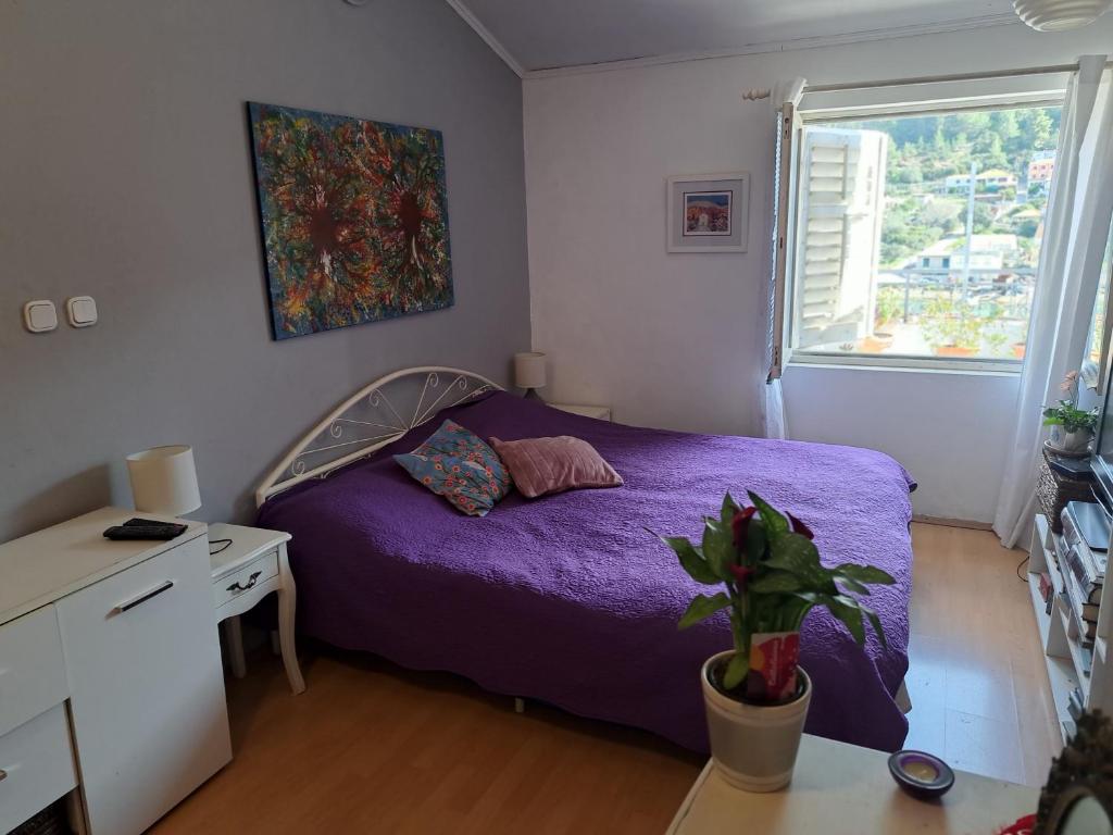 1 dormitorio con cama morada y ventana en Smještaj Latis en Vela Luka