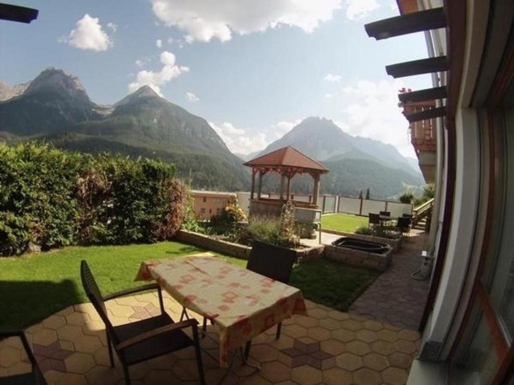 een patio met een tafel, een prieel en bergen bij Alvetern Tschuetta in Scuol