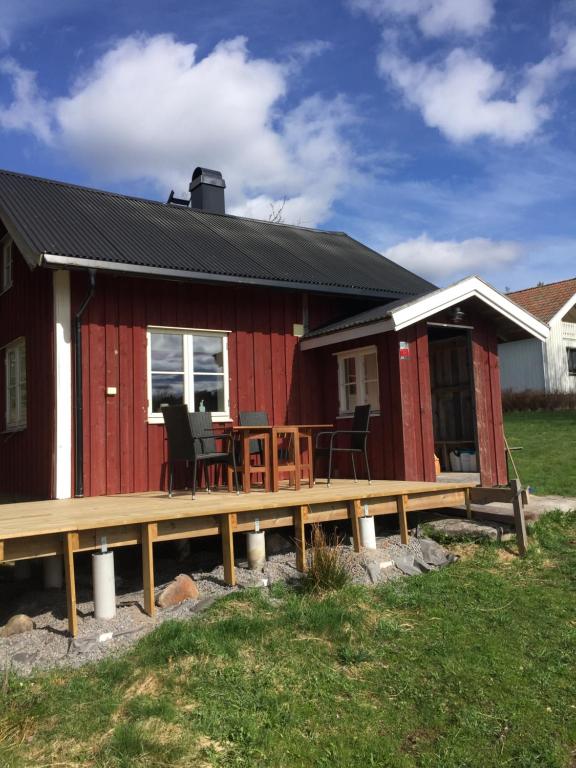 a red house with a deck and a table at Stuga vid viltåker nära norska gränsen in Strömstad
