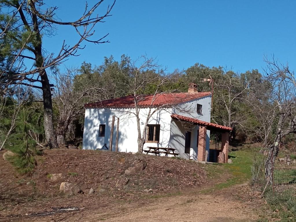 a small white house with a red roof on a hill at Viviendas Rurales del Robledo in Castaño de Robledo
