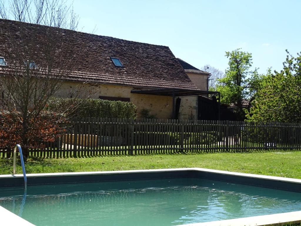 ein Pool vor einem Haus mit einem Zaun in der Unterkunft Gîte Un ange passe en Périgord in Le Buisson de Cadouin