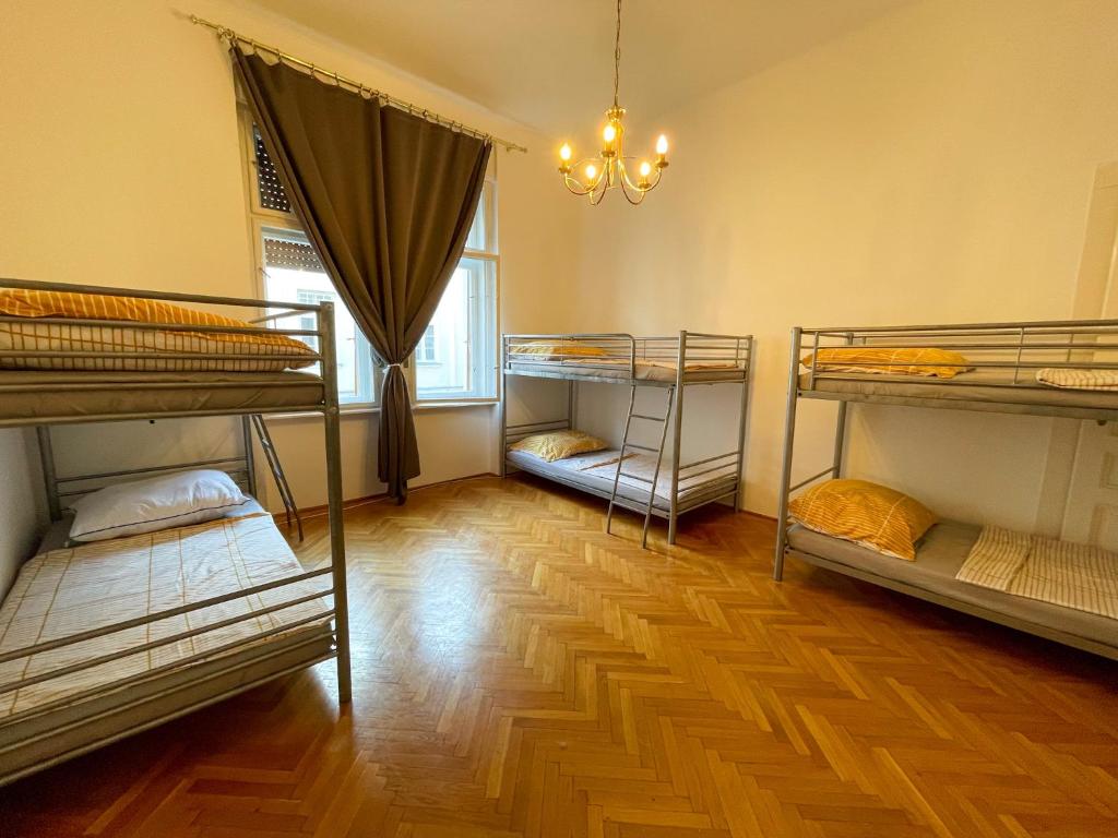 Habitación con 4 literas y suelo de madera. en Centrum Hostel en Pécs