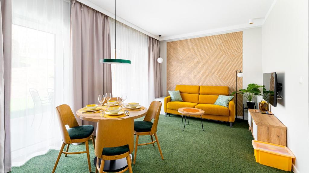 sala de estar con mesa y sofá amarillo en Apartamenty Sun & Snow Wczasowa 17 en Świeradów-Zdrój