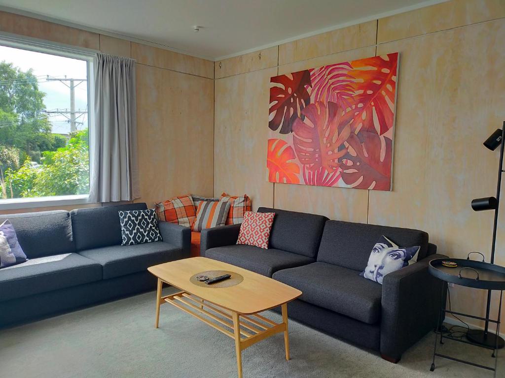 uma sala de estar com um sofá e uma mesa em Relax in Kenmure em Dunedin