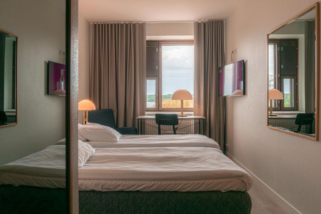 a hotel room with two beds and a mirror at Summer Hotel Tott in Savonlinna