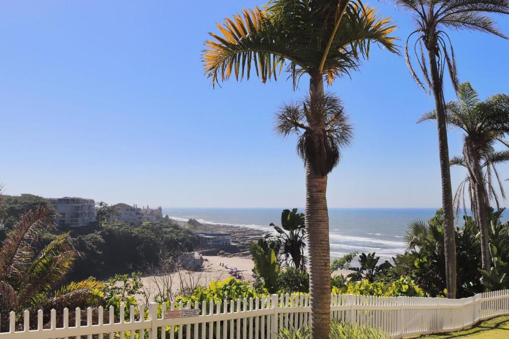 a palm tree in front of a white fence and the beach at Launa La Crete 78 in Margate