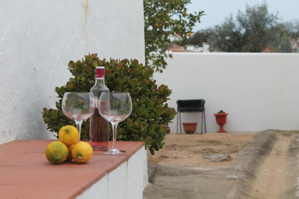 Dois copos de vinho e fruta na mesa. em Casa das Correias em Évora Monte