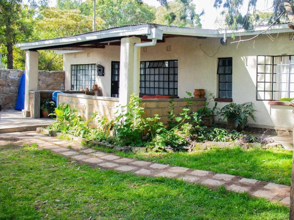 une maison avec une terrasse couverte et une cour herbeuse dans l'établissement Stone Camp Naivasha, à Naivasha