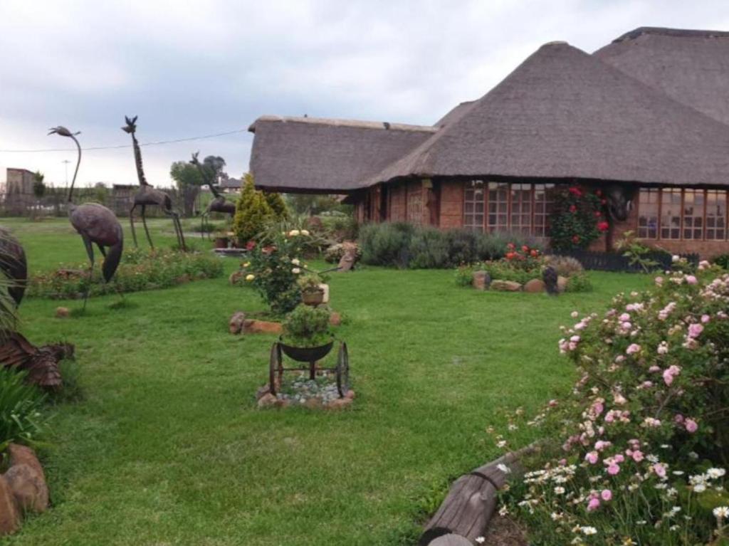 una casa con un patio con un jardinero sentado en el césped en Linglela Lodge, en Estcourt