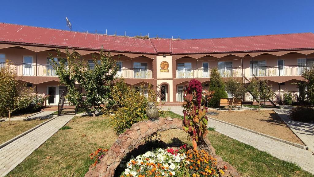 a large building with a flower garden in front of it at Hotel Natalia in Kaji-Say