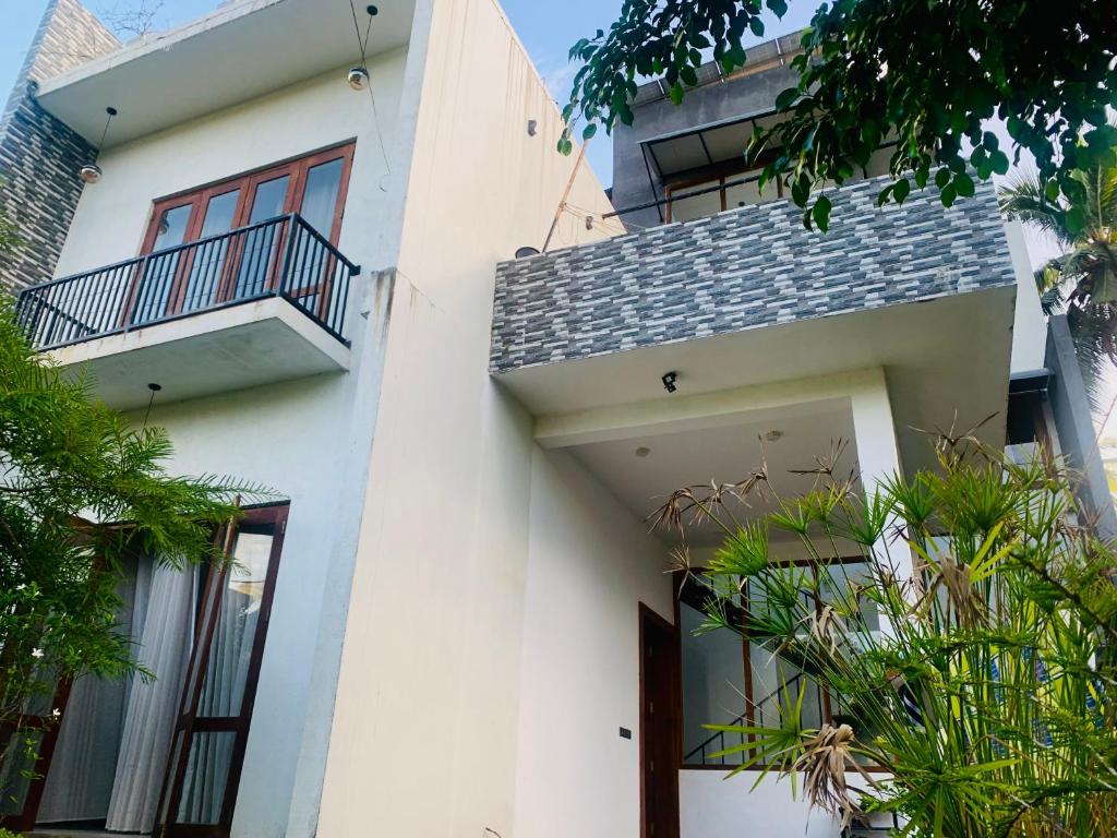 ein weißes Haus mit einem Balkon und Pflanzen in der Unterkunft Jungle city Hostel in Galle