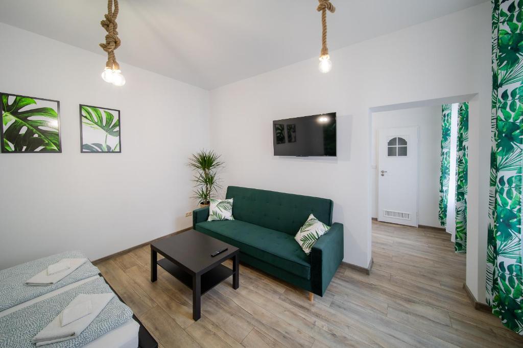 - un salon avec un canapé vert et une table dans l'établissement Jungle Vision Apartment - Rynek, à Carolinensiel