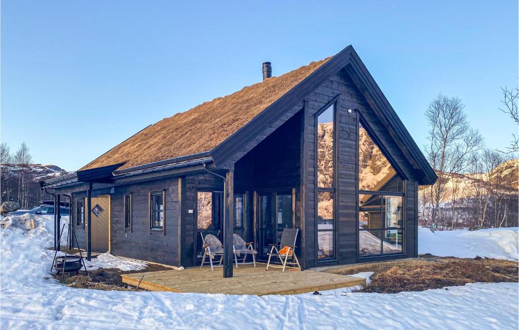 a log cabin with two chairs in the snow at Lovely Home In Vikes With Kitchen in Vikeså