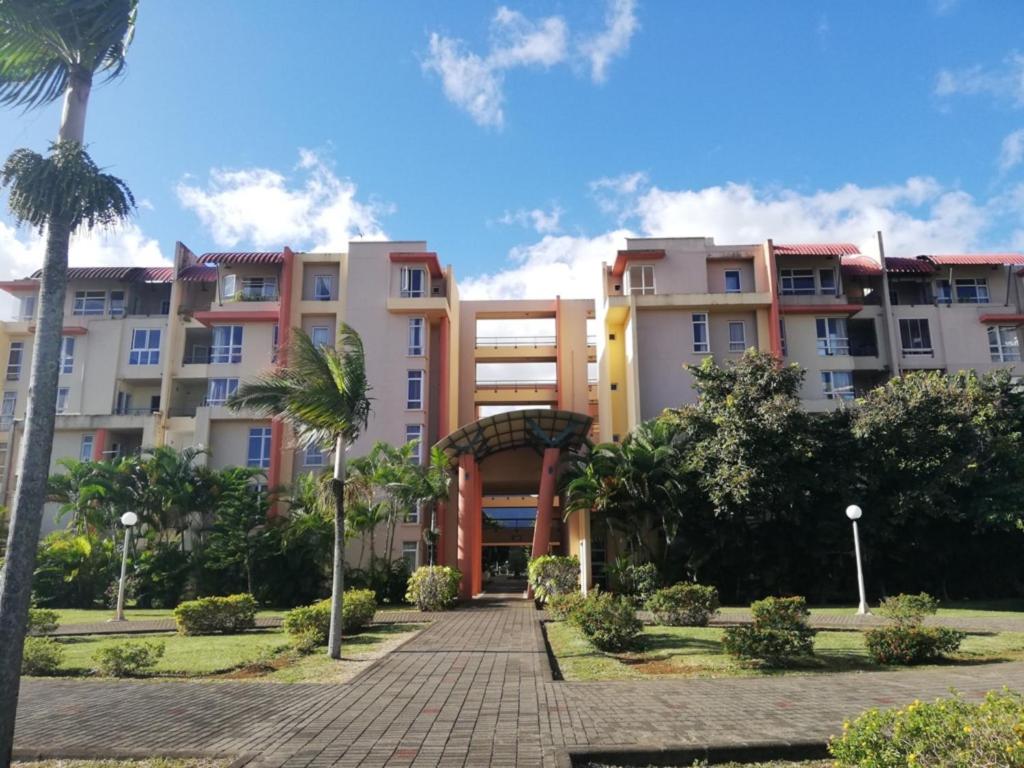 szereg budynków apartamentowych w parku z palmami w obiekcie Cosy Apartment in Ebene w mieście Quatre Bornes