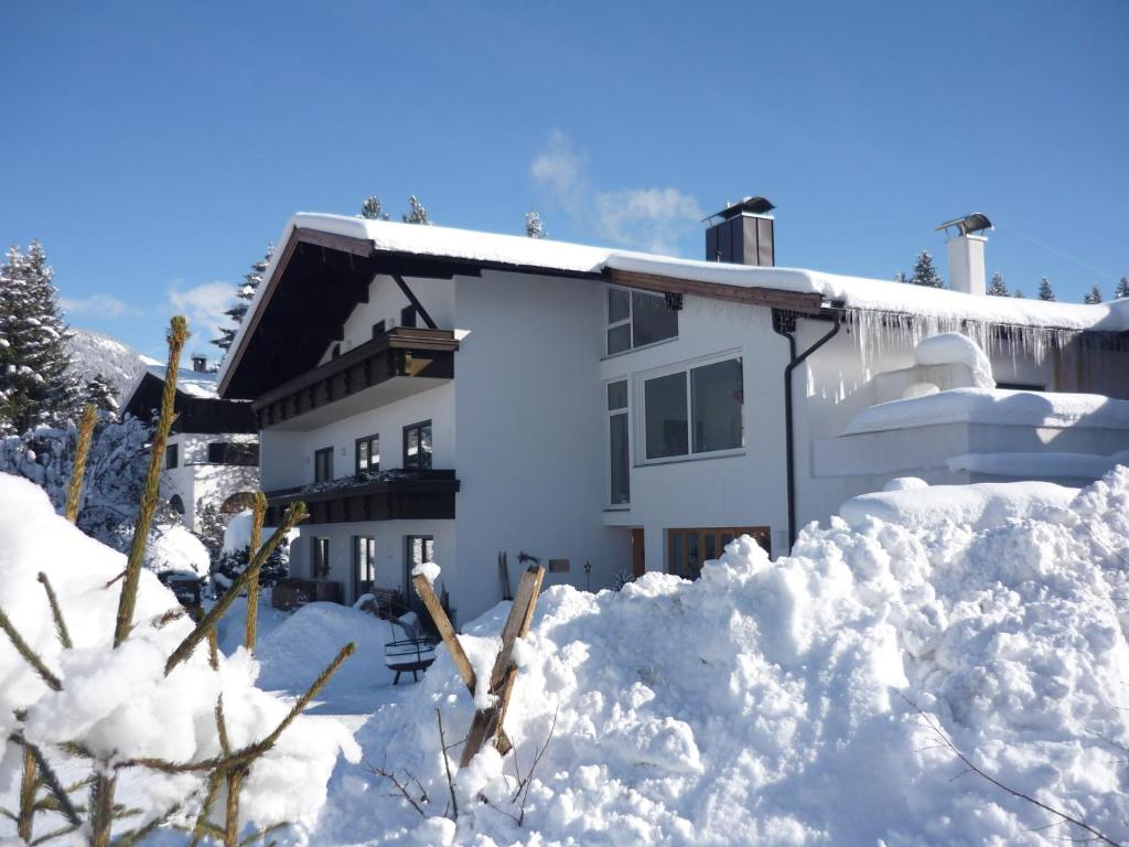 a house covered in snow with a pile of snow at Landhaus Almdorf in Sankt Johann in Tirol