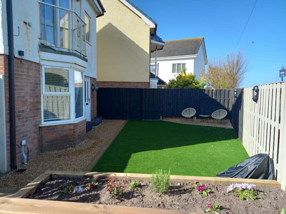a backyard with a green lawn in front of a house at Amazing Beach House, Sleeps 8, Pet Friendly in Trearddur