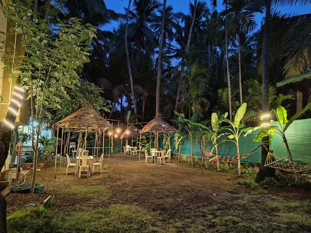 a group of tables and chairs next to a pool at night at Mauli Cottage in Kashid