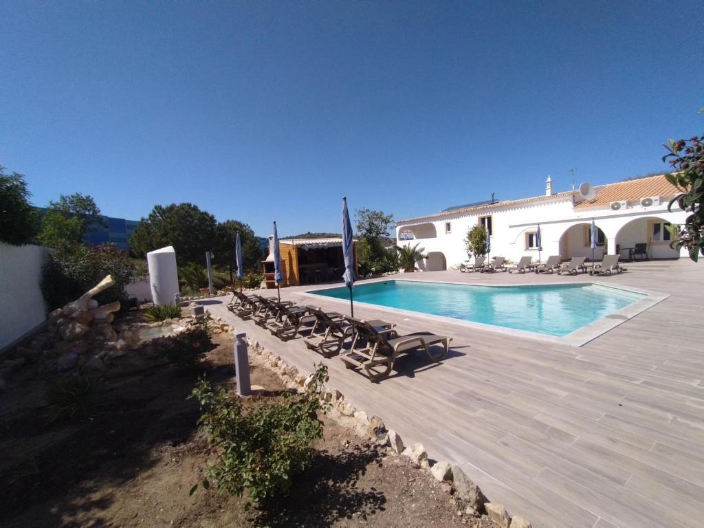 a swimming pool with lounge chairs and a building at Pérola de Sandy in Paderne