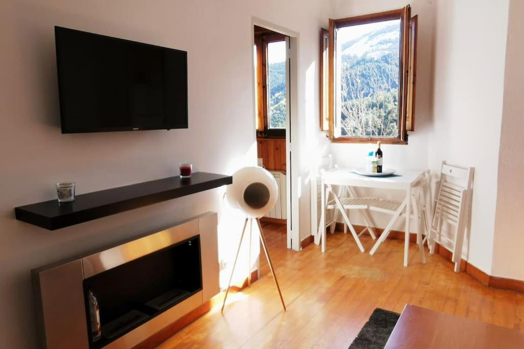 sala de estar con chimenea y TV en la pared en Apartamento acogedor en La Molina, 2hab, Wi Fi en La Molina Alp
