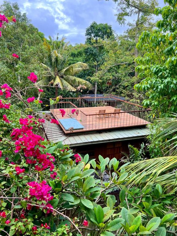 a garden with a deck and pink flowers at Grün Resort Uluwatu in Uluwatu