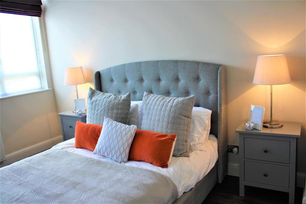 1 dormitorio con 1 cama con almohadas de color naranja y blanco en Penthouse in Old Street, en Londres