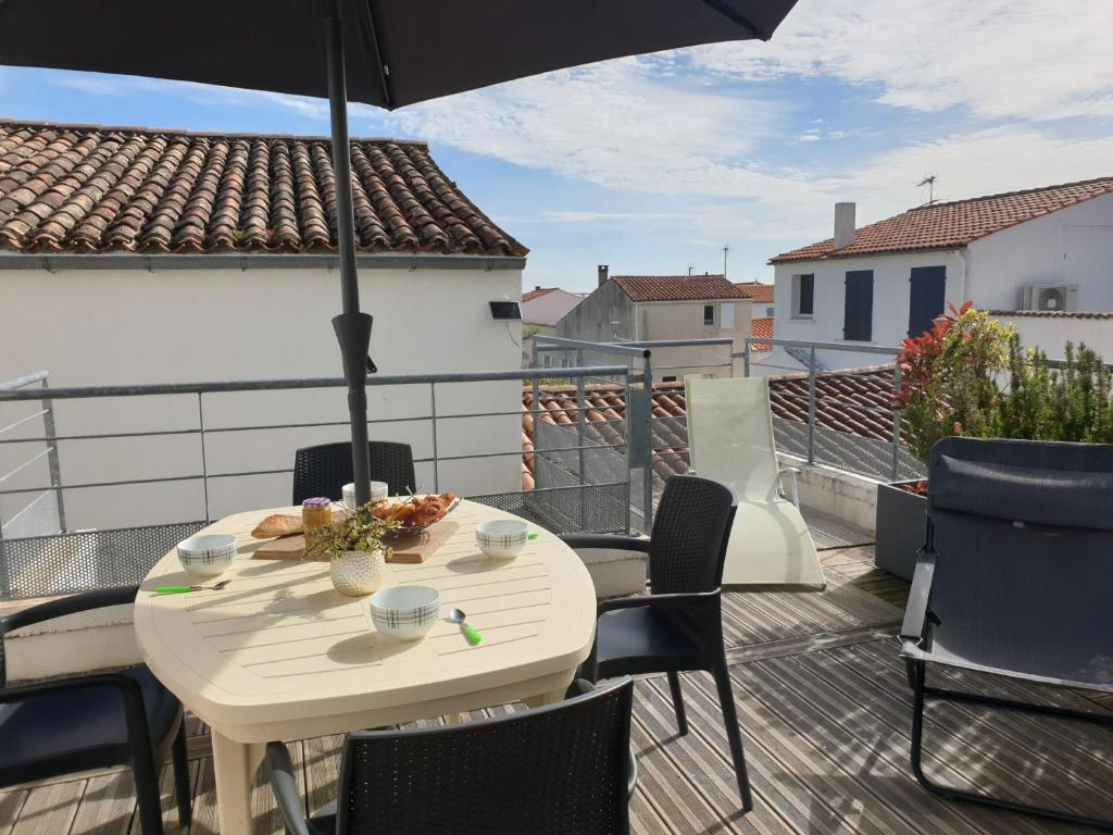 a table and chairs on a balcony with an umbrella at La Belle Cordière in Saint-Trojan-les-Bains