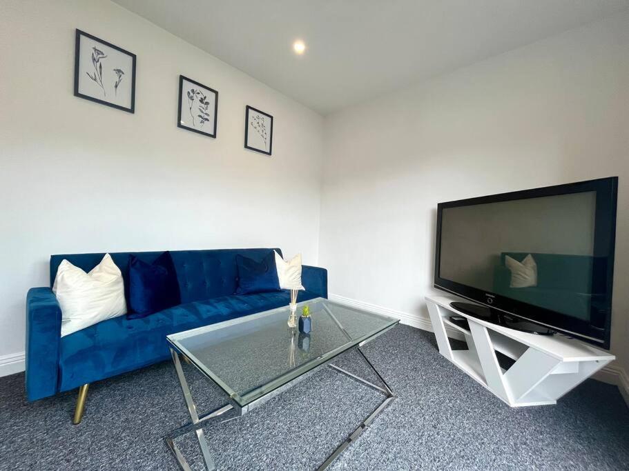 a living room with a blue couch and a tv at Lorne Park Road, Bournemouth in Bournemouth