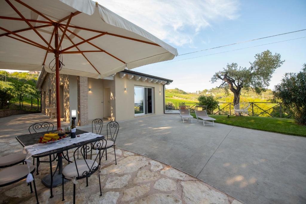 un patio con mesa, sillas y sombrilla en Dimora Campo delle Mura - Charming House en Acquaviva Picena