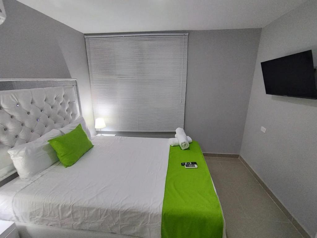 a bedroom with a bed with a green blanket on it at Bm-14G Charming Cartagena Lodge with Shared Pool and Private Terrace in Cartagena de Indias
