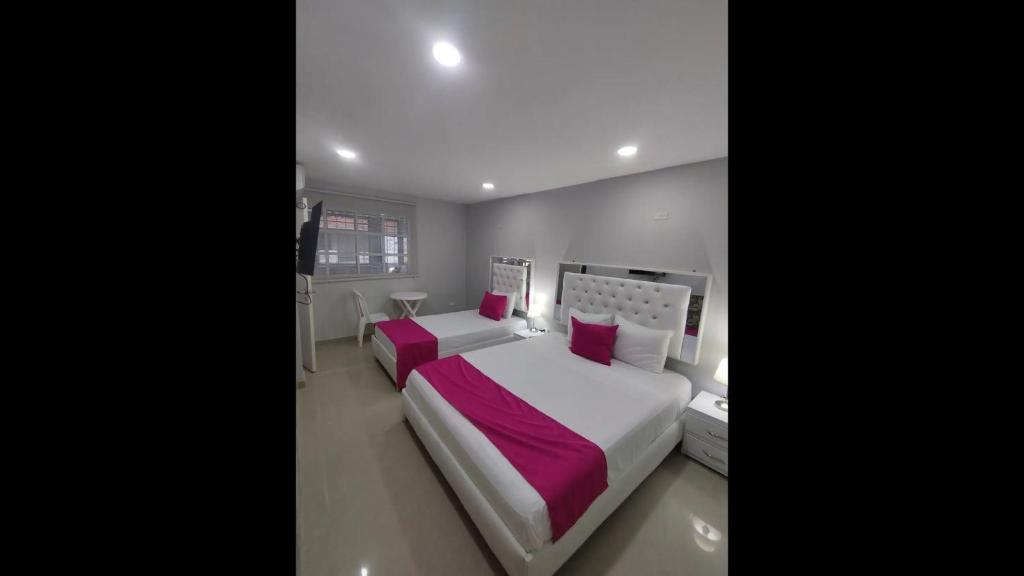 a bedroom with two beds with pink pillows at Bm-1 room near the sea with air conditioning and WIFI in Cartagena de Indias