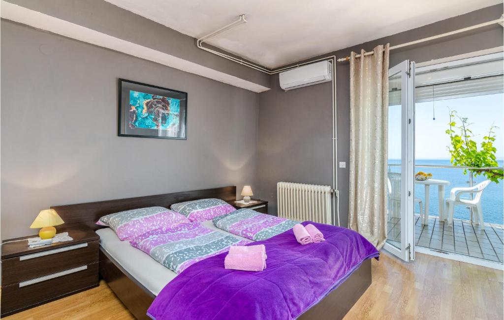 sypialnia z łóżkiem z fioletową pościelą i balkonem w obiekcie Lovely Apartment In Stara Baska w mieście Stara Baška