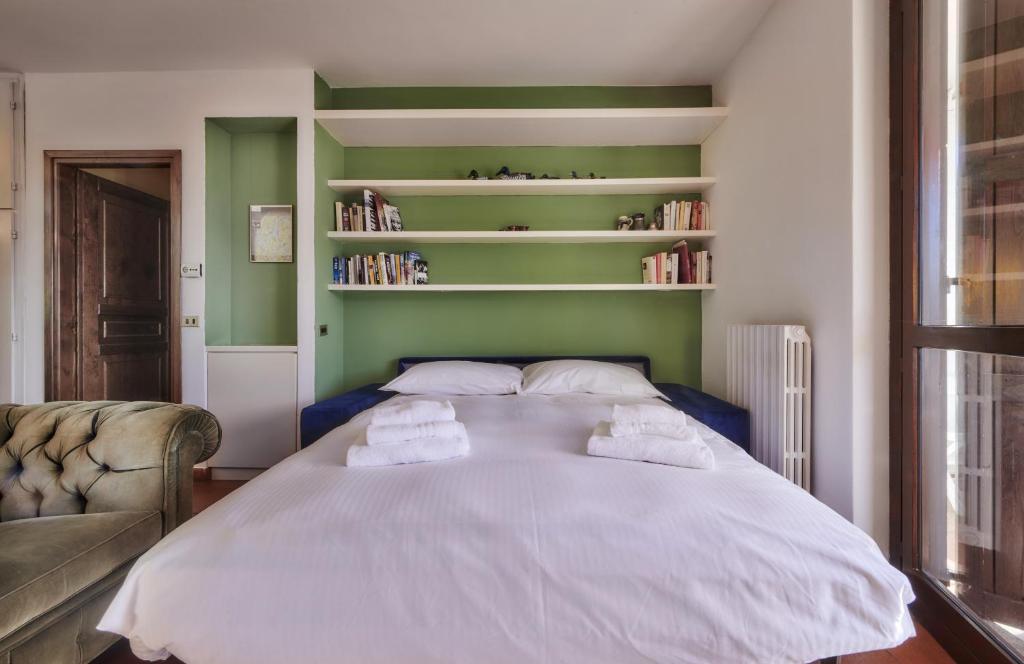 um quarto com uma grande cama branca com estantes de livros em Claudias flat em Lierna