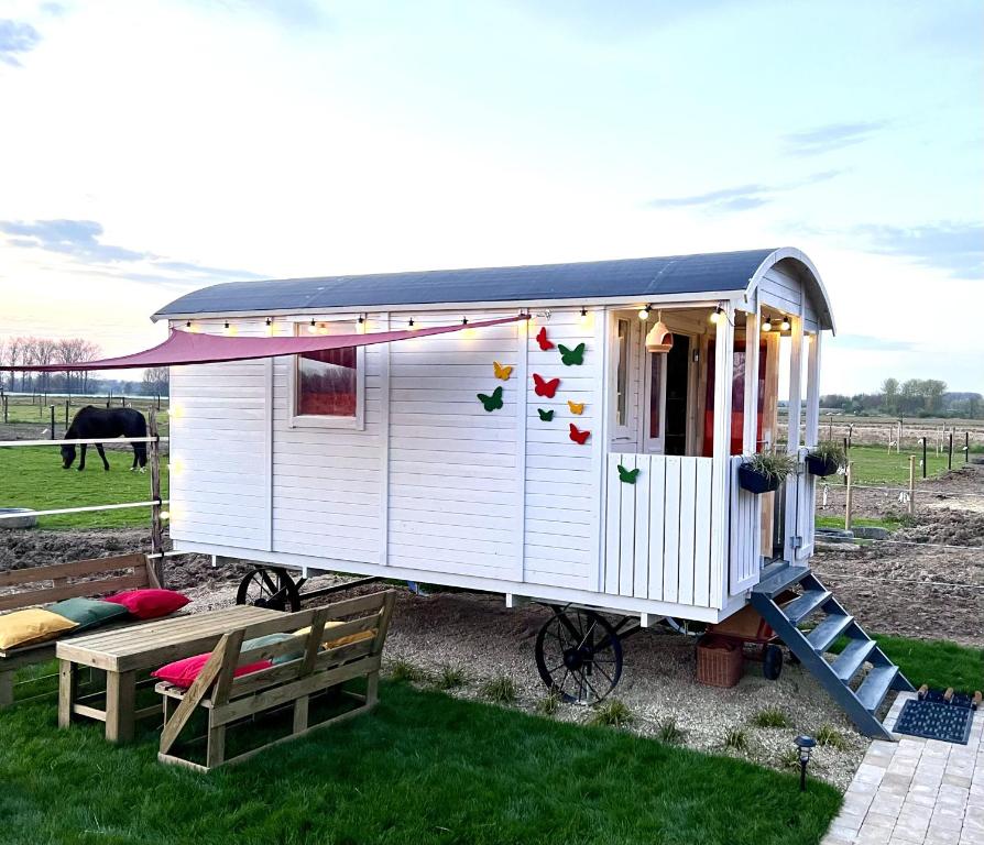 une petite maison blanche avec une véranda et un banc dans l'établissement Ontwaken tussen de paarden, à Helen-Bos