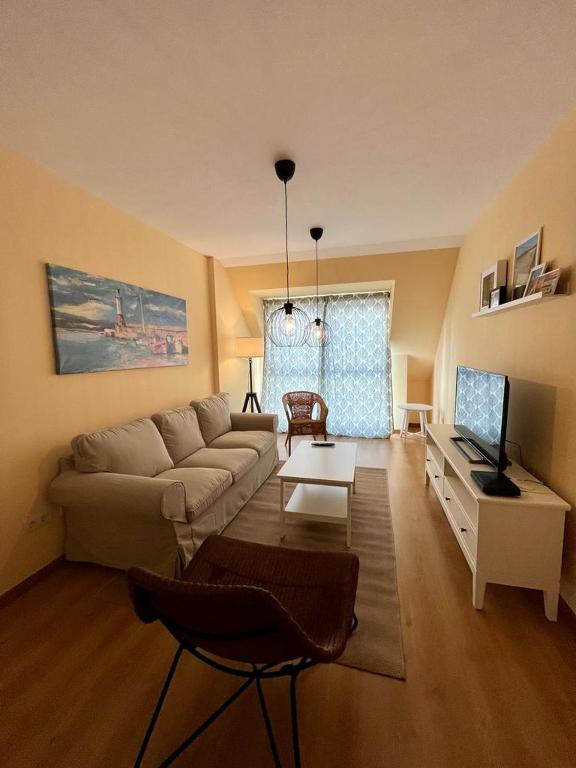 uma sala de estar com um sofá e uma televisão em Centro de Miño - Pumariega em Miño